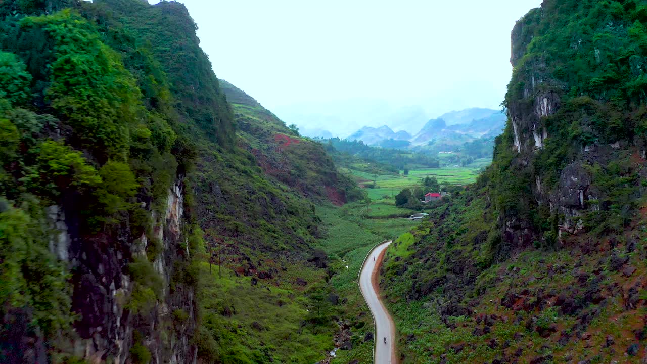 오토바이의 분주한 도로는 두 개의 산을 가로질러 베트남 북부의 안개 낀 뒷산 사이에 무성한 농지를 드러내고 있습니다.