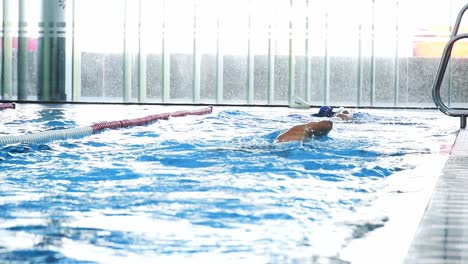 slow motion shot of two professional athletic swimmers swimming in blue pool