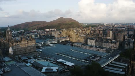 aerial shot pushing over the waverley train station and into edinburgh's downtown buildings