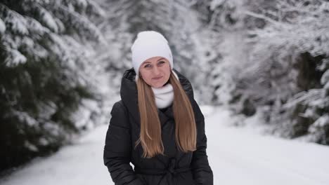the woman is warmly dressed walks in the winter forest and enjoys the winter the woman is warmly dressed walks in the winter forest and enjoys the winter beautiful smiling confident young white woman in the middle of christmas trees happy winter time