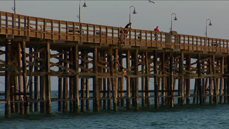 young men jump from a pier into the sea