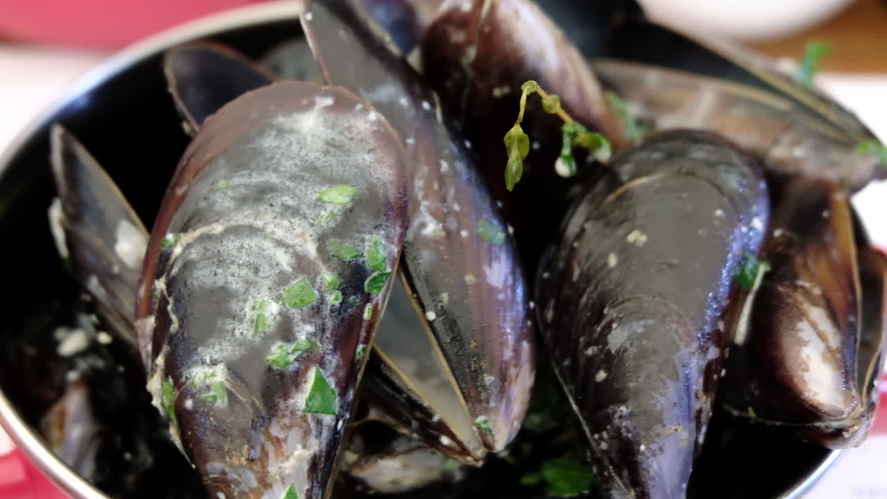 Close up of a bowl of cooked mussels with parsley