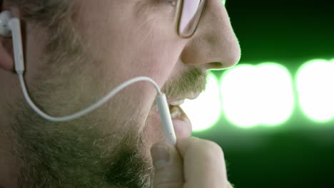 bearded caucasian man in profile talks on phone via inline earbud mic