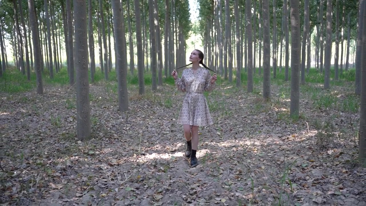 Una donna aggraziata passeggia tranquillamente attraverso una splendida foresta serena, ricca di alberi alti