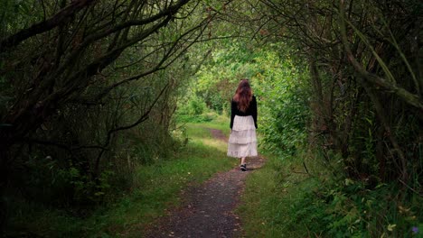 a girl dressed in black was walking on a forest path