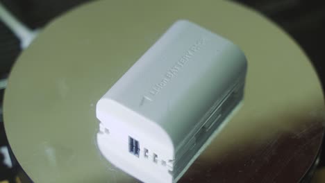 a rotating close up shot of a white lithium camera battery, slow motion 4k