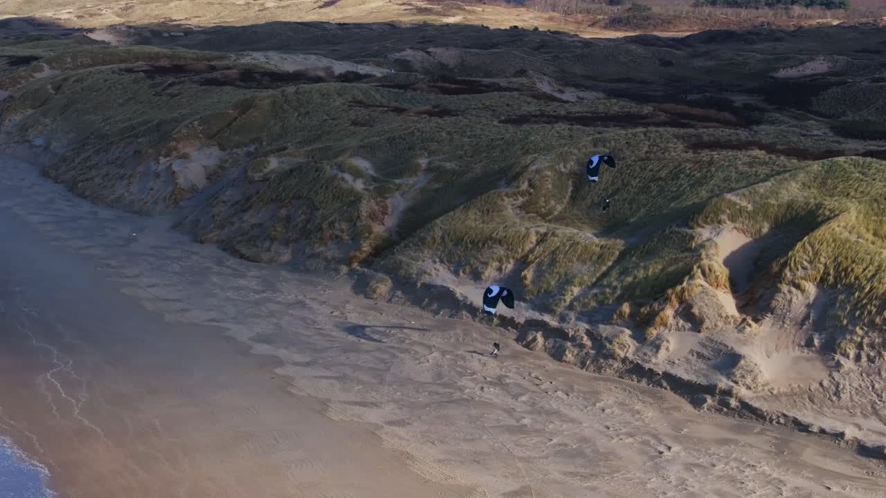 kiteboarding en una playa con dunas de arena