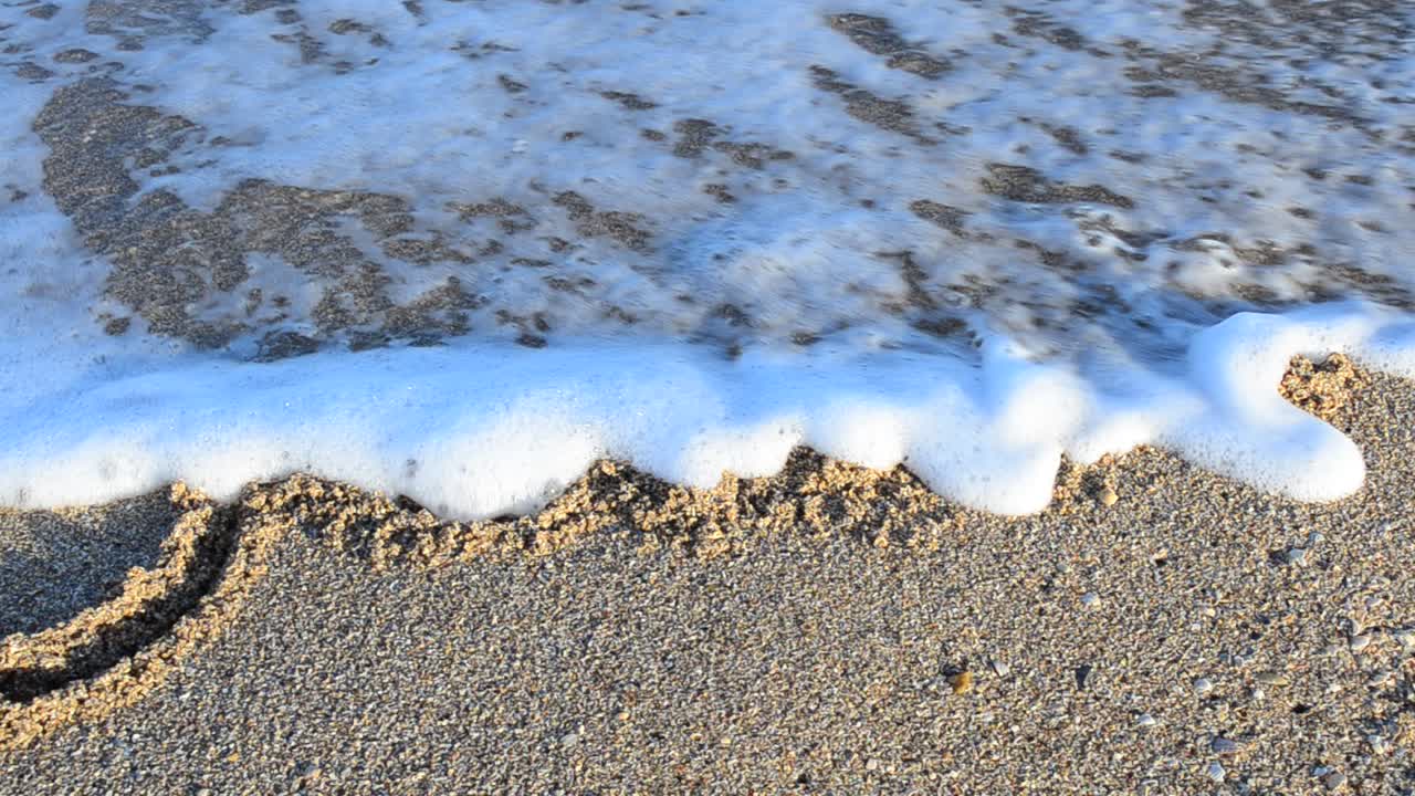 Inscription June on sand. The inscription is washed away by a sea wave. Shooting on the beach