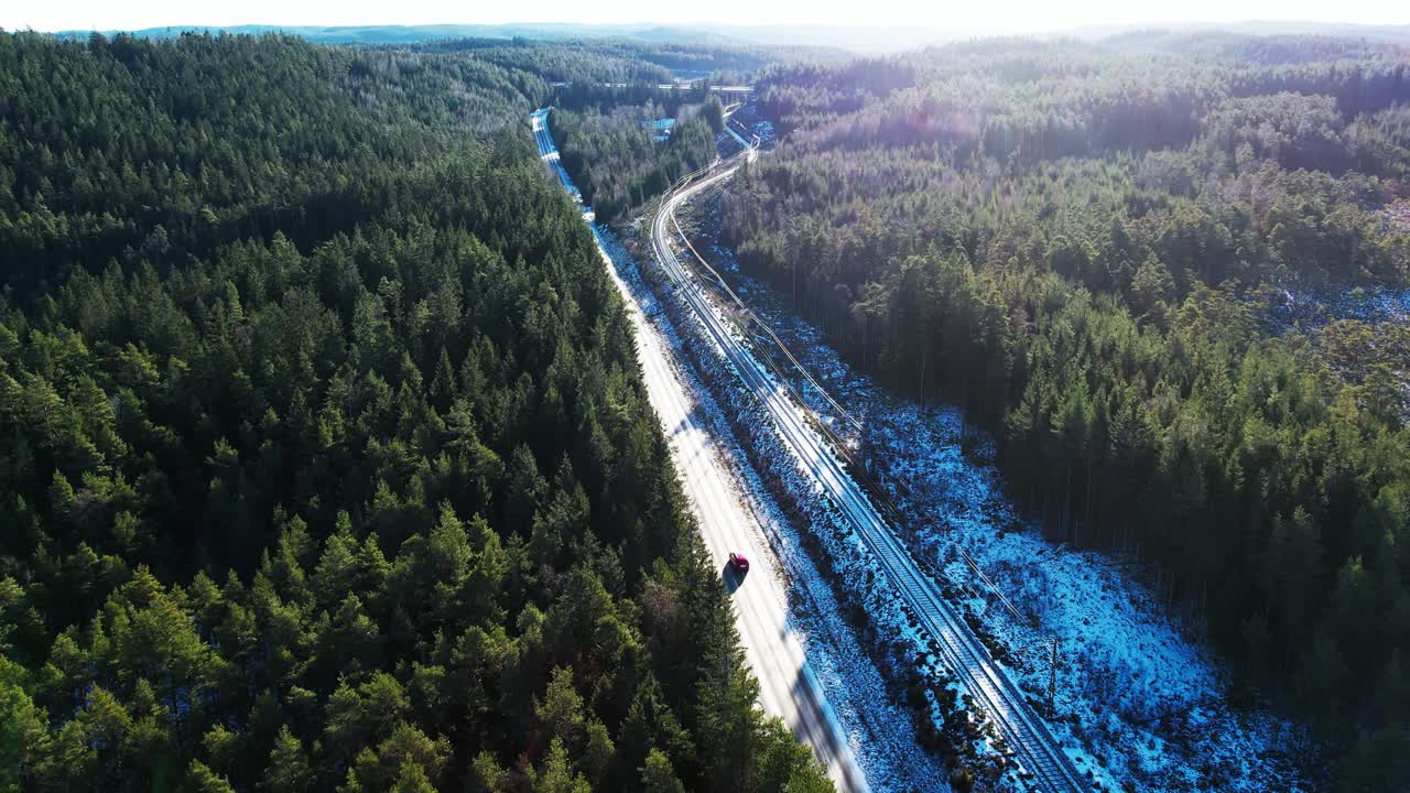 Aerial view of forested hills and snow lined road running beside railway in Klippans Nature Reserve, Sweden