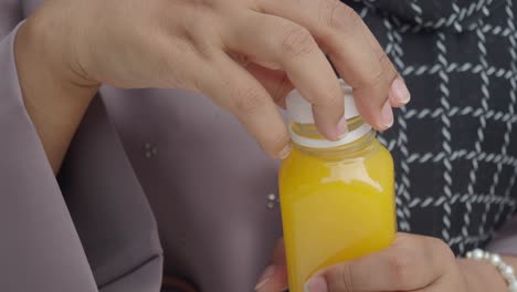 woman opening a bottle of orange juice