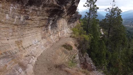 drone flight following narrow hiking trail near the steep rock cliffs, captured in wild mountain area and untouched nature in patagonia, argentina, south america