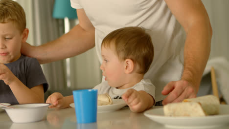 kids having food with father on dining table 4k