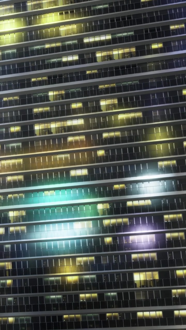City building at night with colorful lights in windows