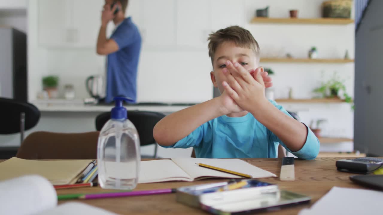 Caucasian boy sitting at table with school work