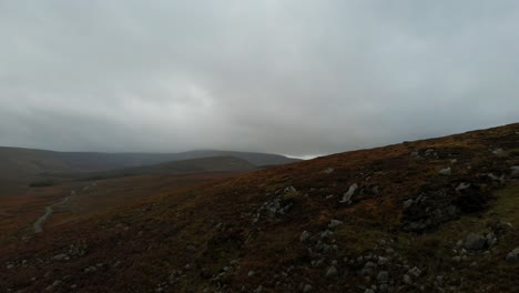 Revealing-aerial-shot-of-mountainous-grasslands-in-Ireland-during-an-overcast-day