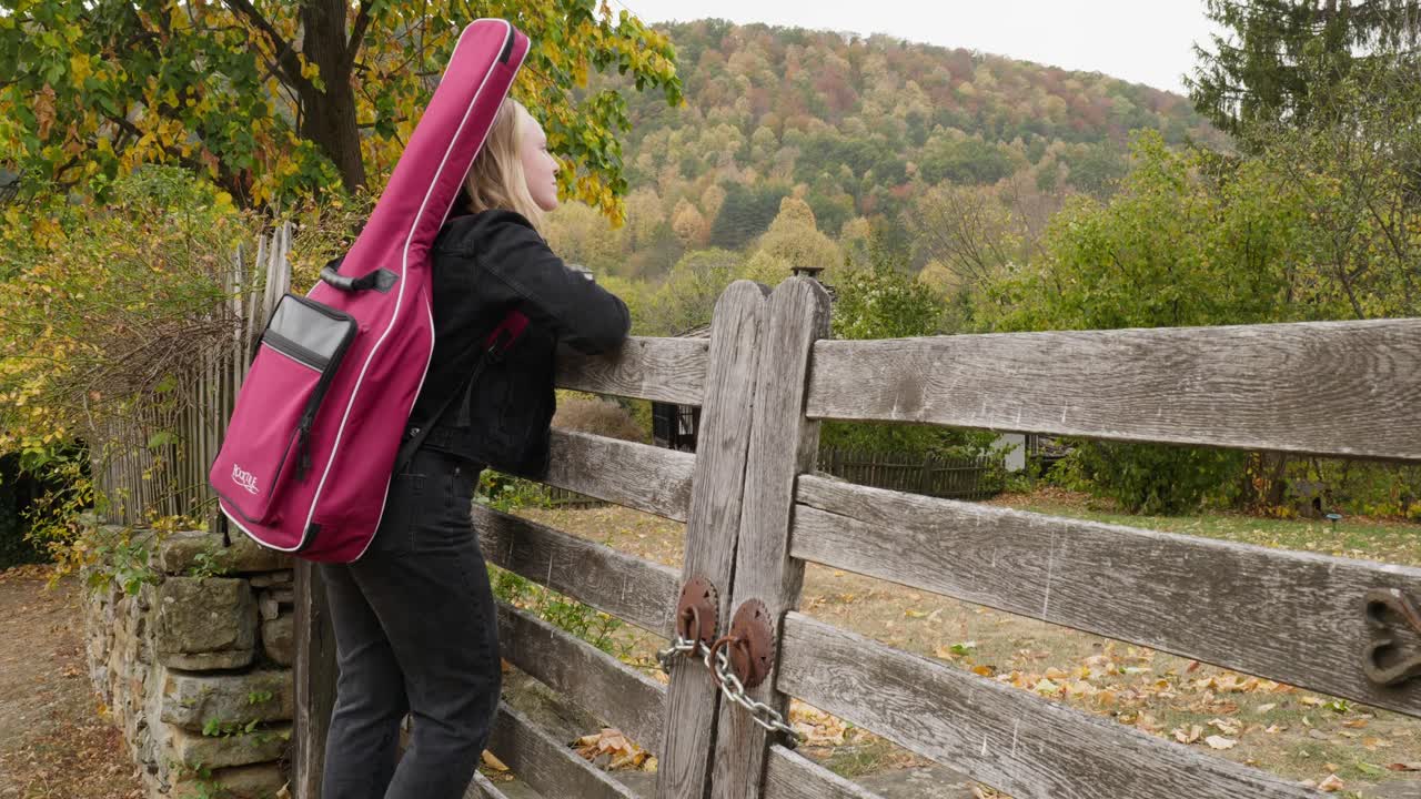 hermoso joven músico en la puerta de madera vistas de la escena del bosque de otoño