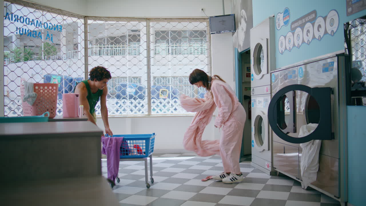 재미있는 커플이 세탁소에서 장난을 치고 있습니다. 재미있는 친구들이 옷을 습니다.