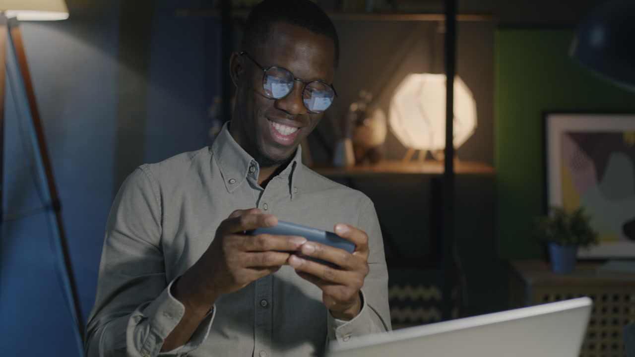 Man playing a game on his phone at night in home office