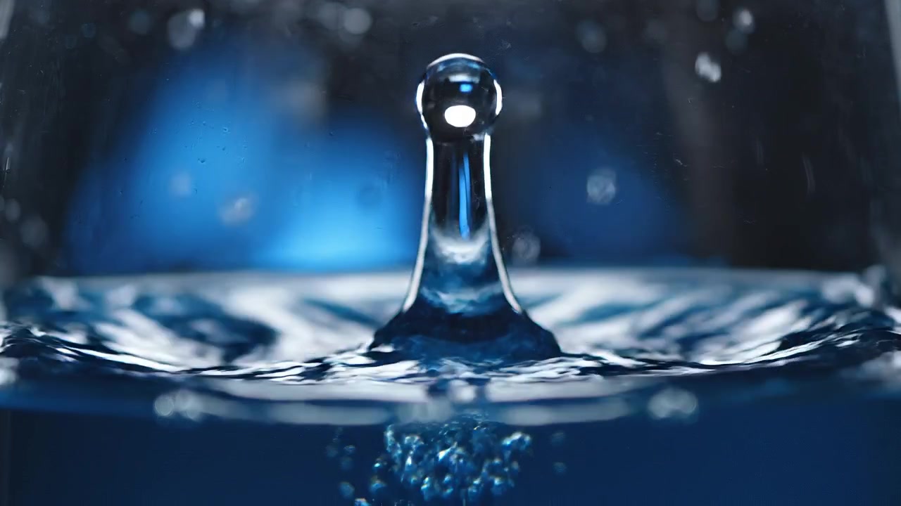 Gros plan d'une goutte d'eau tombant dans un liquide bleu