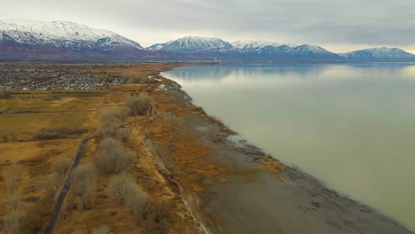 volando sobre el lago utah a lo largo de la costa hacia un desarrollo suburbano en saratoga springs