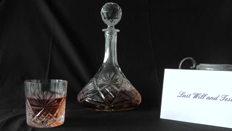 an envelope holding a will is put on a desk beside a glass of whisky and whisky decanter