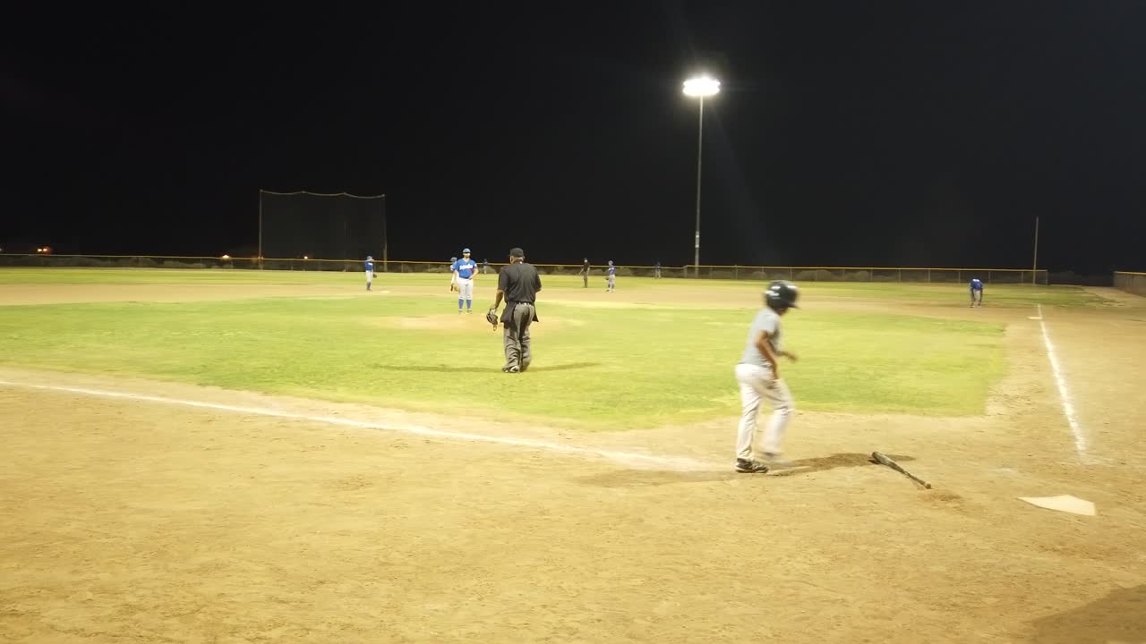 A young baseball batter hitting a home run and running all four bases - Wide shot