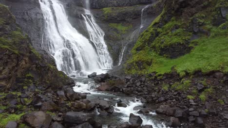 Waterfall-of-Glymur-cascading-down-rocky-cliff-in-Iceland,-low-angle-aerial-view