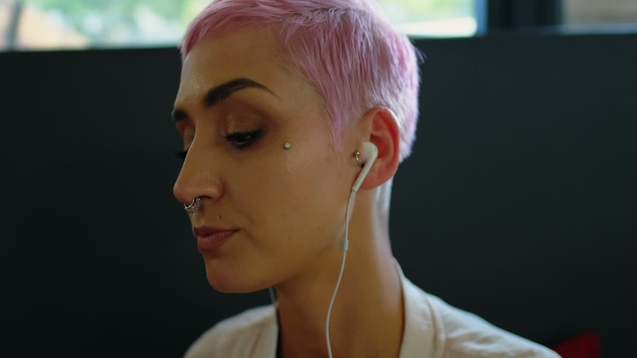 mujer escuchando música mientras usa una computadora portátil en un café 4k