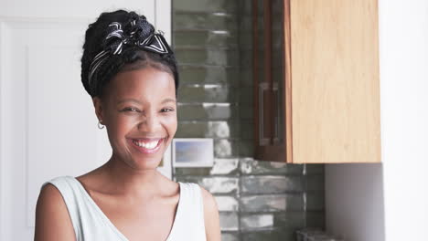 Young-African-American-woman-smiles-brightly-at-home,-with-copy-space