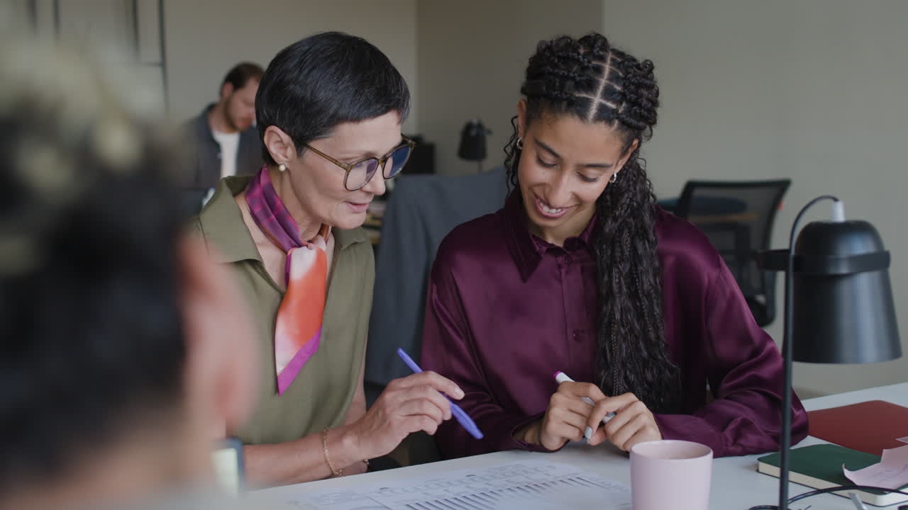 Two Businesswomen Collaborating and Discussing Documents in an Office