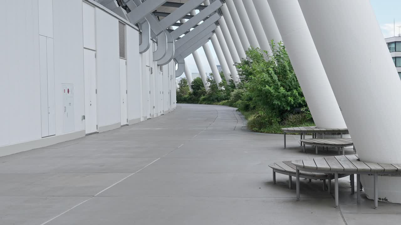 A calm, modern walkway with distinctive white pillars at Tokyo's National Stadium, a perfect blend of design and nature