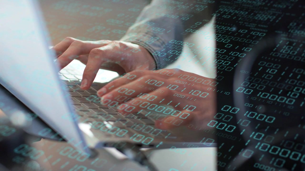 Office worker starting typing on laptop keyboard, binary overlay flowing across keyboard for coding