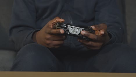 primer plano niño sosteniendo el controlador en casa sentado en el sofá jugando videojuegos