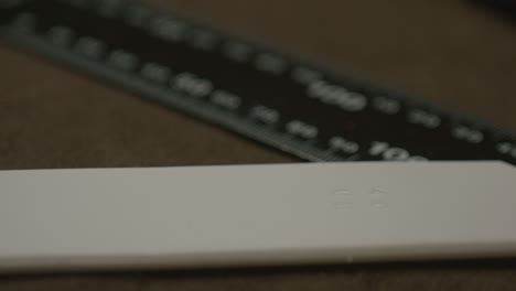 detailed view of a white leather edge burnisher with embossed markings, placed beside a black measuring ruler on a brown surface.