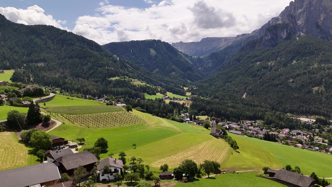Splendide riprese con drone 4K che panoramicano Castelrotto, un'incantevole città storica in Alto Adige che presenta l'iconica Chiesa di San Valentino, circondata dalle imponenti cime delle Dolomiti.