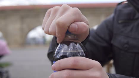 Vista-De-Cerca-De-Las-Manos-Del-Hombre-Desenroscando-La-Parte-Superior-De-Una-Botella-De-Refresco-En-El-Café-De-La-Calle.-Filmado-En-4k