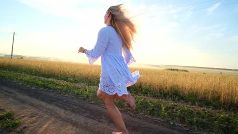 woman running barefoot through a field at sunrise