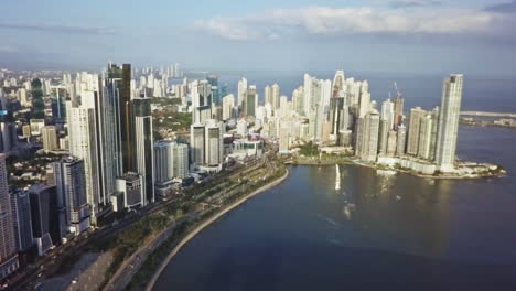 Aerial-shot-truck-right-pan-left-of-Panama-City-bay-and-buildings-with-sea-below,-Panama