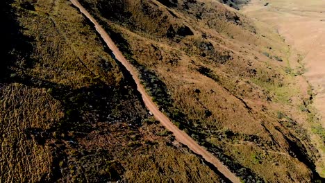 Vista-Aérea-Siguiendo-A-Ciclistas-De-Montaña-Bajando-Un-Paso-De-Montaña-60fps