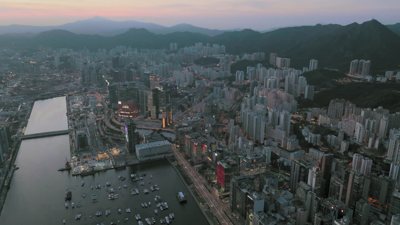 toma panorámica aérea del área de la bahía de kowloon, hong kong después del atardecer con la silueta de la cordillera en el fondo