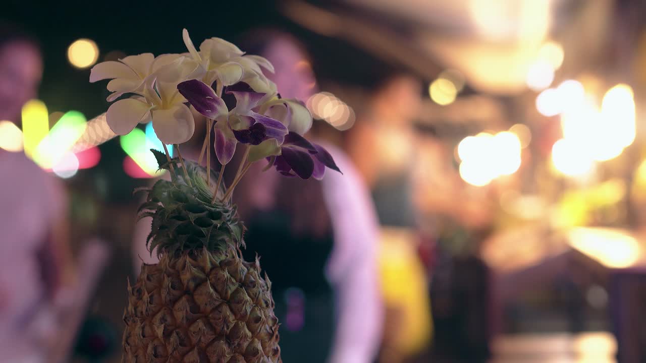 piña con orquídeas en flor contra luces borrosas