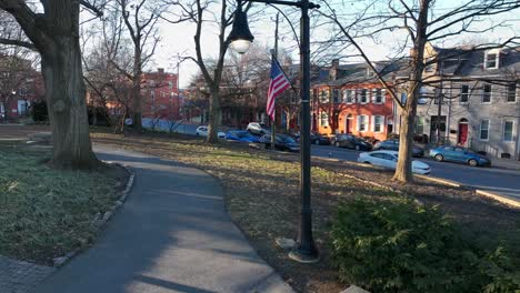 aerial view of american flag waving on cold winter day in park beside city housing