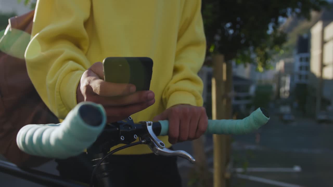 Transgender adult with a bike and using a phone