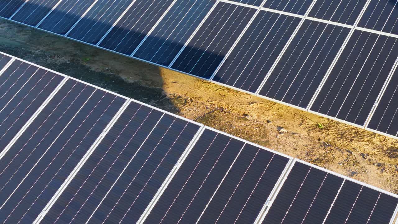 Drone footage captures rows of solar panels in a sunlit field, highlighting renewable energy technology and sustainability