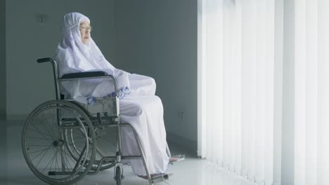senior muslim woman doing salat in a wheelchair