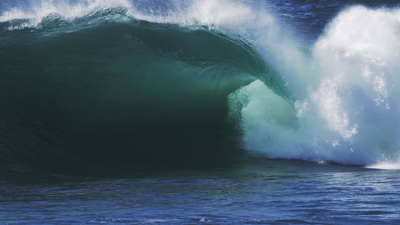 Barreling wave curls perfectly with rich mist rising and light glowing through it