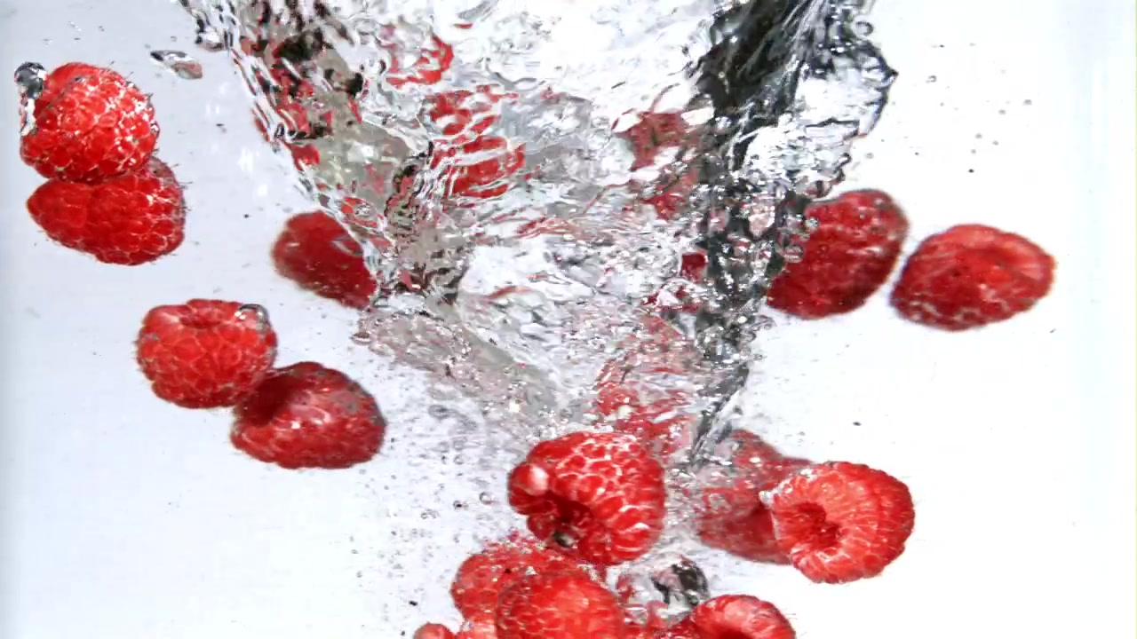 Fresh Red Raspberries Falling and Splashing in Clear Water