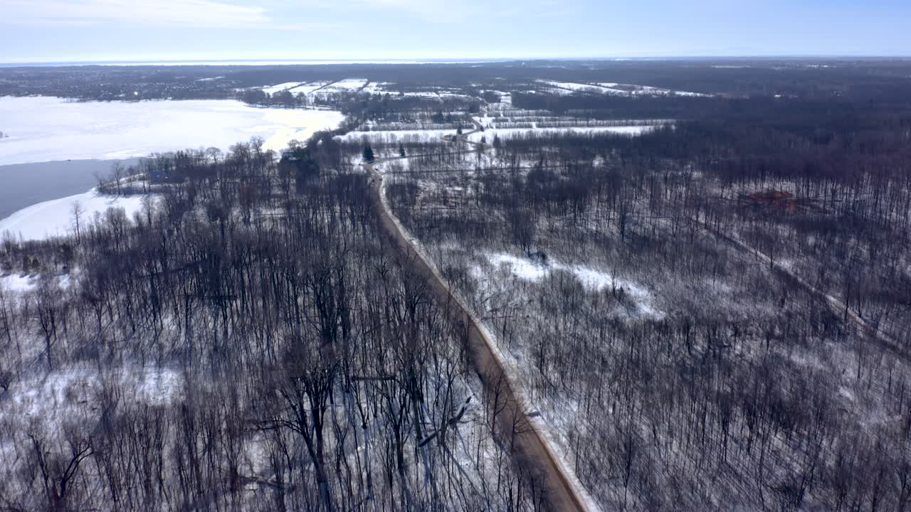 drone retrocediendo sobre un bosque en invierno siguiendo a un camión en la carretera