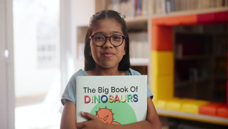 girl holding a book about dinosaurs