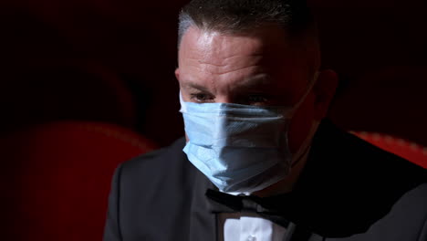 lonely and sad visitor sits in empty theater hall alone. person sits on a red chair during pandemic.